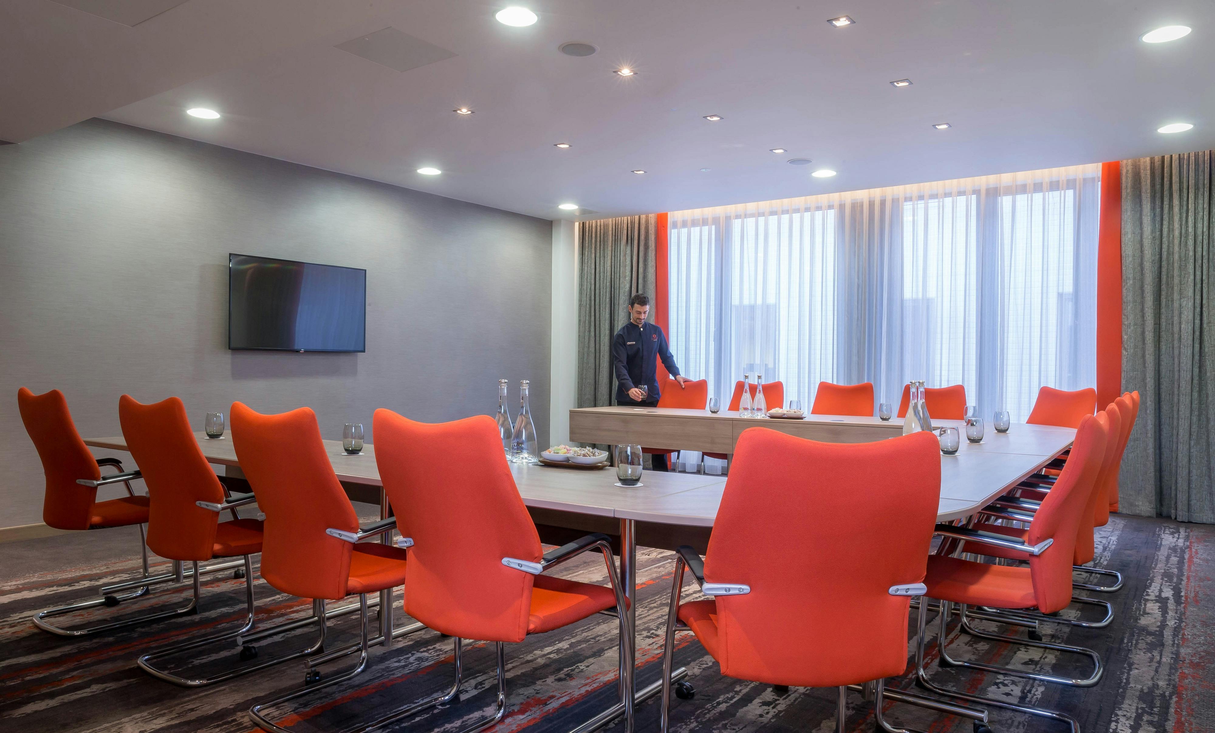 Devonshire Suite at Clayton Hotel Chiswick, modern meeting room with orange chairs.