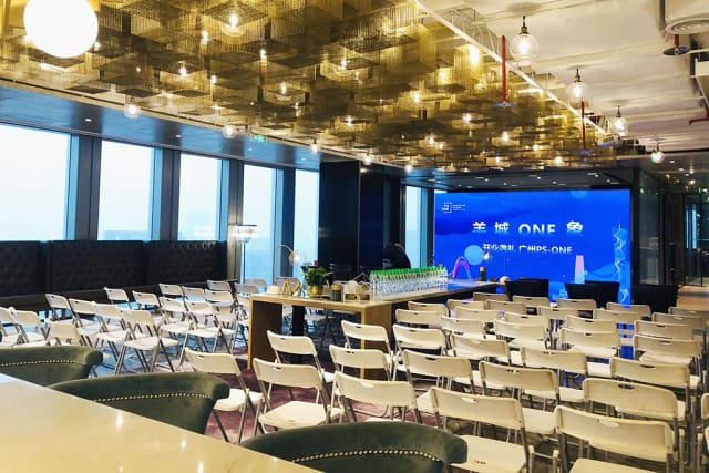 Event space with white chairs and bar, ideal for corporate meetings and conferences.