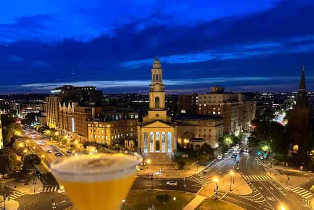 Rooftop bar at Hotel Zena with city skyline and cocktails, ideal for nightlife events.