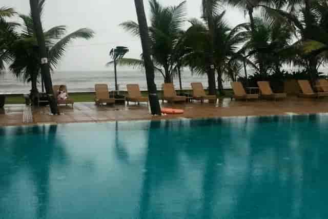 Poolside Lawn at Novotel Mumbai Juhu Beach, ideal for events, features rain-soaked palm trees.
