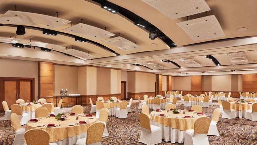 Elegant banquet venue at Vivanta By Taj with gold tablecloths, ideal for conferences.