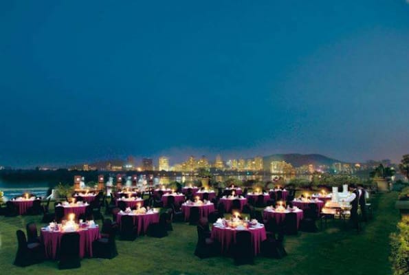 Elegant outdoor event setup with purple tables and city skyline at Renaissance Mumbai.