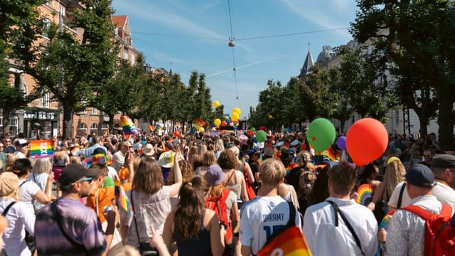 Vibrant crowd celebrating at Copenhagen Pride event with colorful décor.