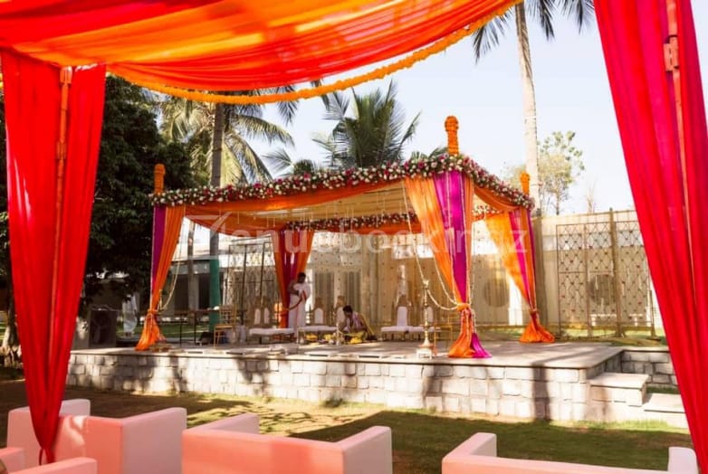 Elegant outdoor wedding venue with vibrant orange and pink drapery, perfect for events.