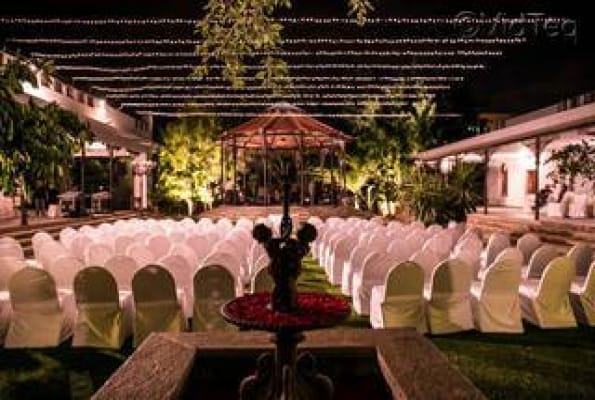 Outdoor conference hall at The Tamarind Tree with white chairs and lush greenery.