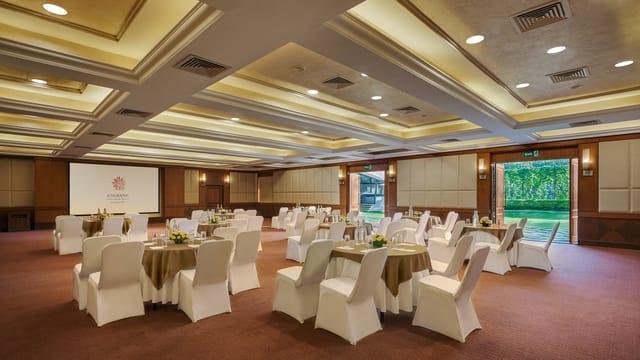 Elegant Burgundy Room set for corporate meeting with round tables and natural light.