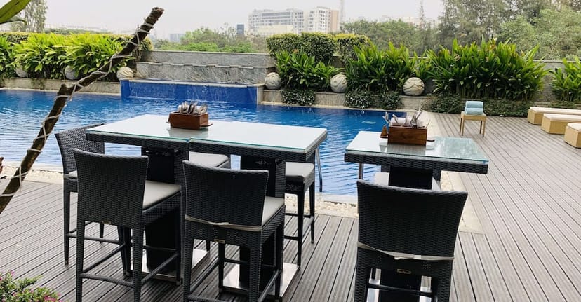 Outdoor meeting space at BG's Bar, Bengaluru with modern seating by a serene pool.