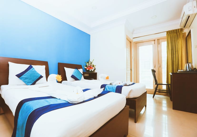 Eco hotel suite with twin beds and blue accent wall, ideal for event attendees.