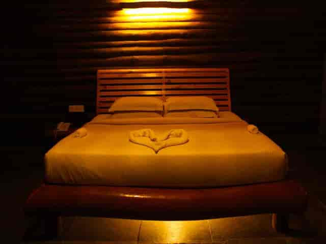 Wooden Cottage bedroom with heart towel art for romantic getaways and luxury retreats.