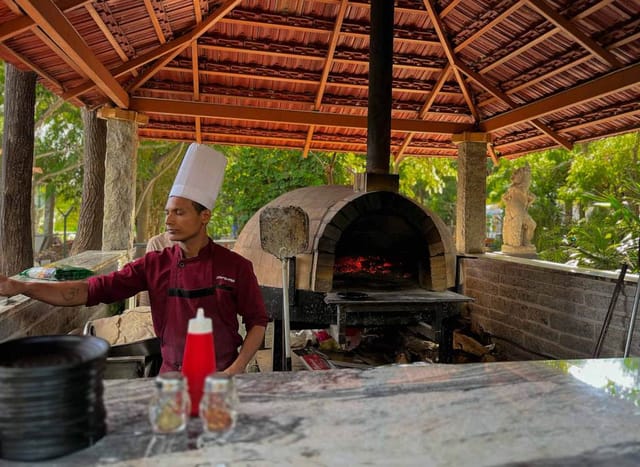 Outdoor kitchen with wood-fired oven at Mango Mist Resorts for culinary events.