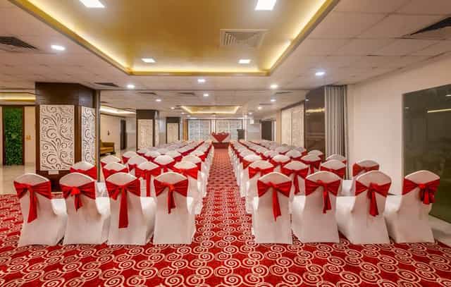Elegant exhibition hall with white chairs and red bows at Golden Palms Hotel & Spa.