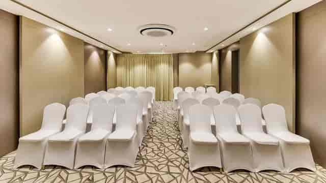Conference center in Ramada Bengaluru: formal event space with white chair covers.