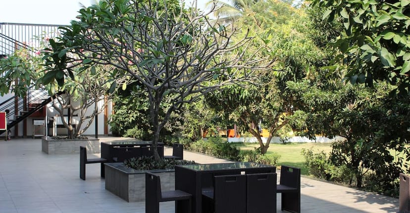 Outdoor meeting space at B 64 Ramada Bengaluru, featuring modern furniture and lush greenery.
