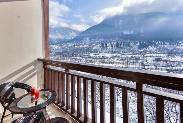 Balcony view hotel retreat in Pahalgam with snow-capped mountains, ideal for corporate events.