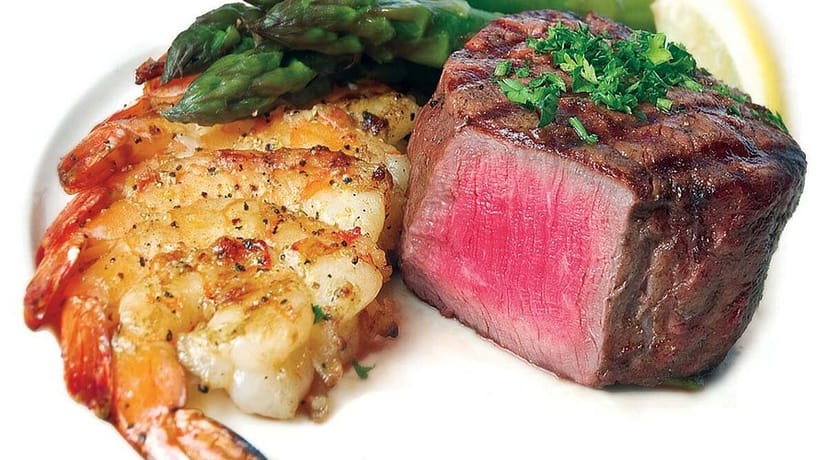 Elegant surf and turf dish with filet mignon and shrimp in upscale Banquet Room setting.