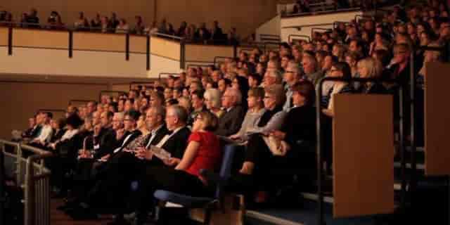 Packed auditorium in Saffron Hall showcases vibrant event with engaged attendees.