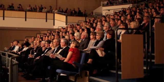 Packed auditorium in Saffron Hall showcases vibrant event with engaged attendees.