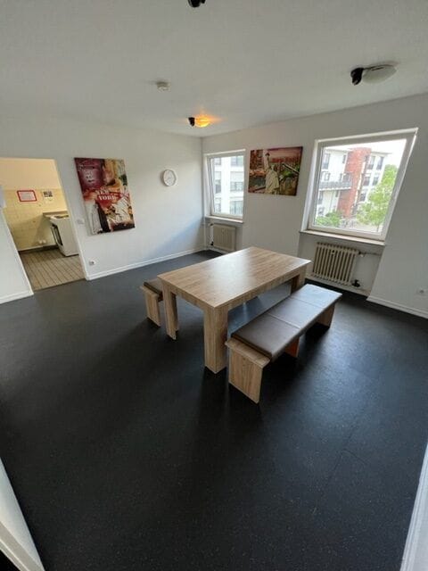 Inviting lounge with wooden table and benches for team meetings at MLKH Studentenwohnheim.