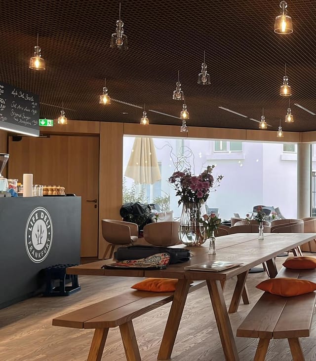 Modern event space with wood table and warm lighting at Life Deli, Jewish Museum Frankfurt.