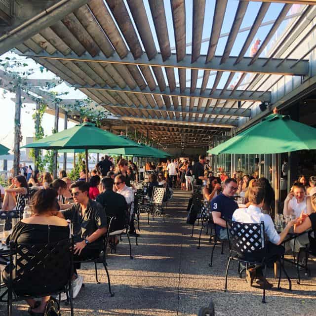 Vibrant outdoor dining patio with green parasols, perfect for social events and networking.