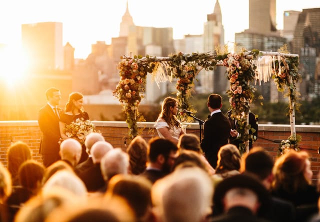 Rooftop wedding ceremony with skyline backdrop at The Bordone LIC, featuring elegant floral decor.