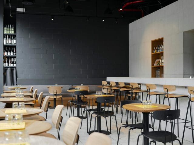 Modern event space in ATLA NOHO with rounded wooden tables, ideal for receptions and networking.