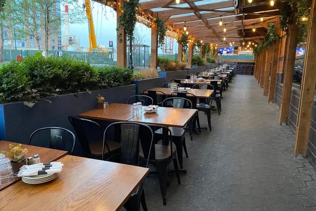 Stylish outdoor bar venue with wooden tables, ideal for summer events and gatherings.