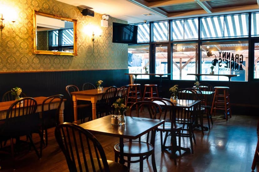 Bar at Granny Annie's Kitchen, featuring wooden seating and elegant floral decor for events.
