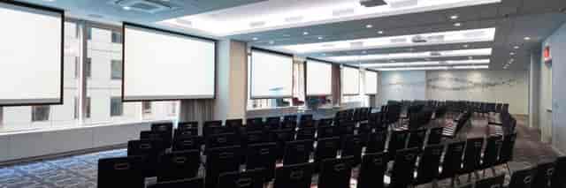 Conference room with black chairs and projection screens for seminars and workshops.
