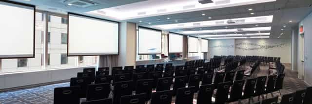 Conference room with black chairs and projection screens for seminars and workshops.