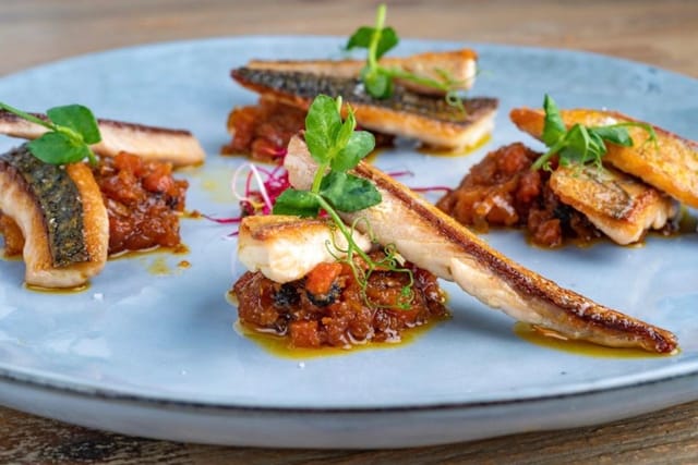 Seared fish dish with vibrant microgreens at Zalamero Taberna for events and dining.