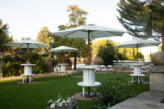 Elegant outdoor event space in Salón de los Espejos, with white umbrellas and lush greenery.