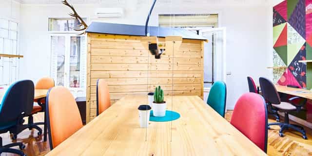 Modern coworking meeting space with a large wooden table, ideal for brainstorming events.