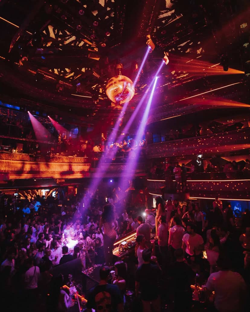 Vibrant nightclub with central dance floor, lasers, and disco ball for lively celebrations.