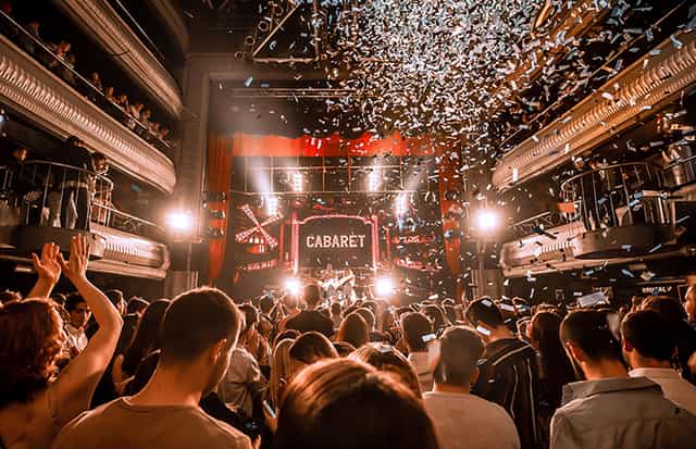 Vibrant cabaret event at Teatro Kapital with dynamic lighting and lively audience.