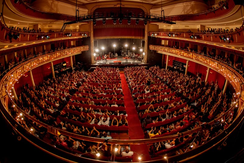 Packed Nuevo Teatro Alcalá auditorium with elegant decor and vibrant audience during a live event.