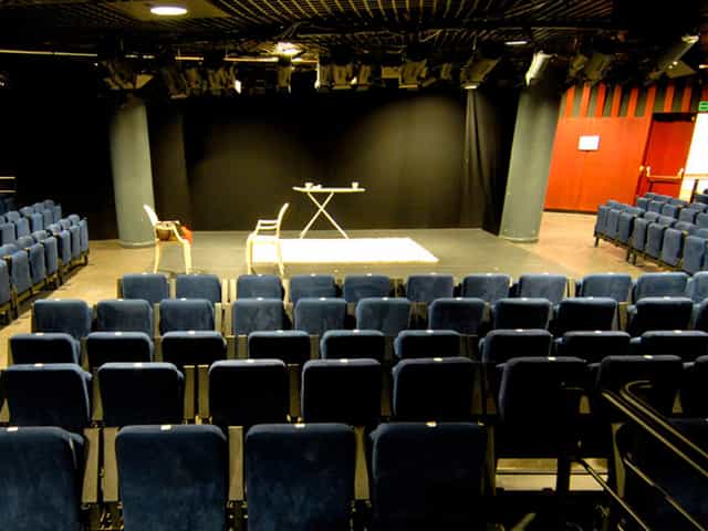 Alt tag: Auditorium at Nuevo Teatro Alcalá with blue chairs, ideal for events and workshops.
