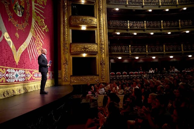 Speaker addressing audience in Teatro Español’s ornate Sala Principal for cultural events.