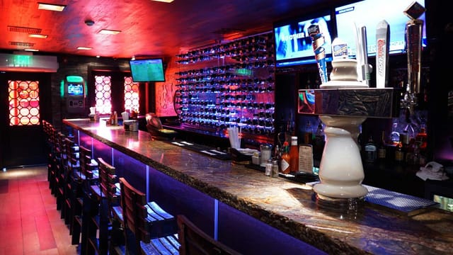 Sleek modern bar in Adega Grill, ideal for networking and casual events with vibrant lighting.