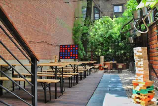 Outdoor Secret Garden at Clinton Hall with wooden tables, ideal for casual events and gatherings.
