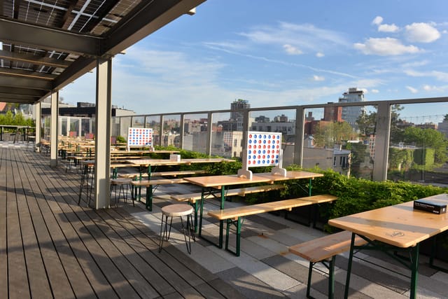Outdoor Secret Garden rooftop venue with wooden tables, ideal for casual gatherings and networking.