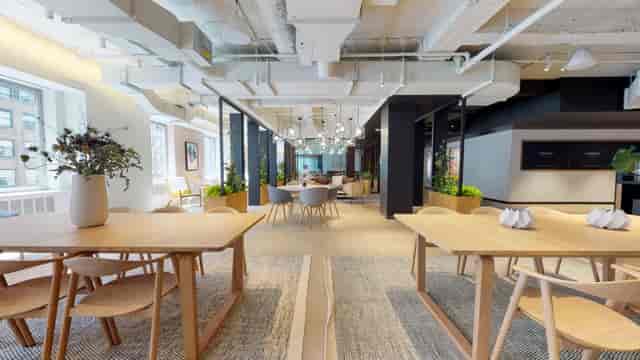 Modern open-concept meeting room with wooden tables for corporate workshops and events.