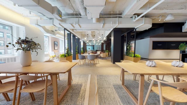 Modern open-concept meeting room with wooden tables for corporate workshops and events.