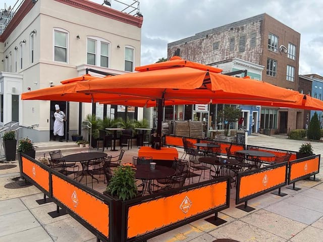 Outdoor bar at The Grill DC with orange umbrellas, ideal for events and gatherings.