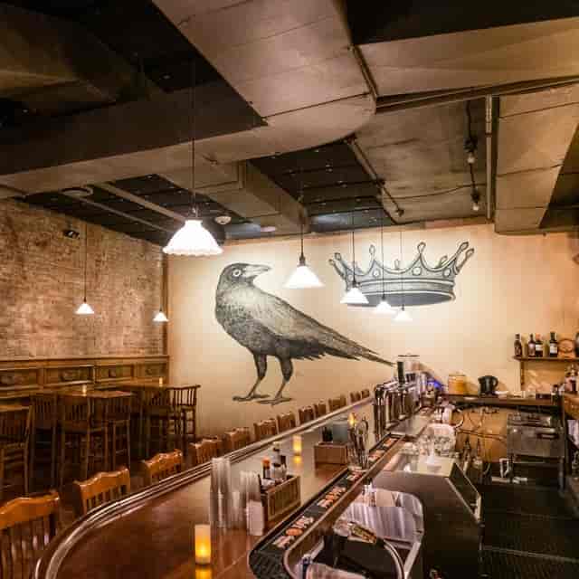 Beer hall at The Crown & Crow with crow mural, perfect for gatherings and workshops.