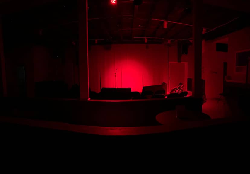 Producer's Meeting in Studio Place with red-lit stage, perfect for performances and networking.