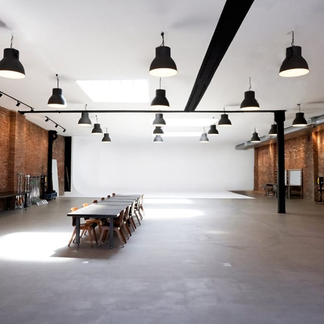 Spacious industrial studio with large windows for corporate events and workshops.