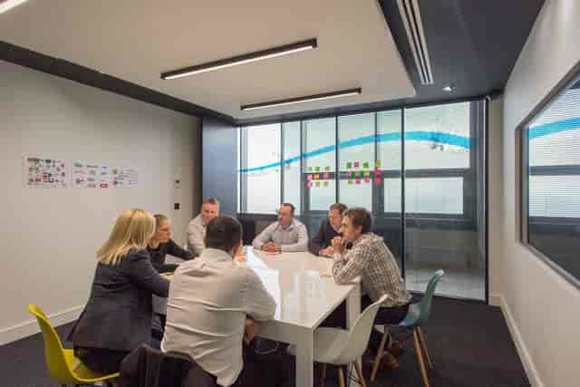 Diverse professionals collaborating in a modern meeting room with sticky notes for brainstorming.
