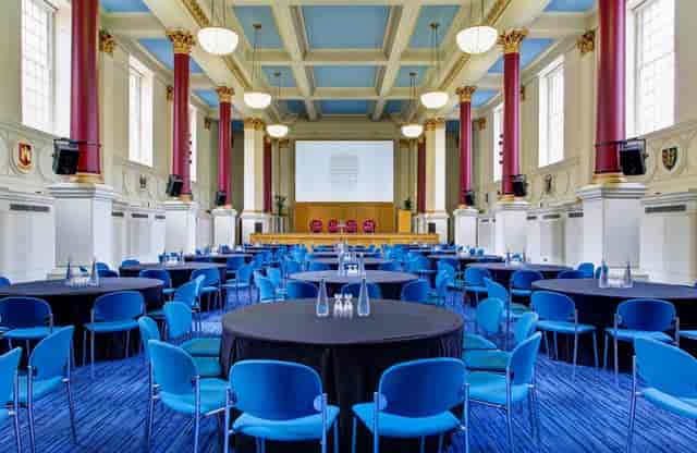 Conference room with round tables and blue chairs, perfect for meetings and events.