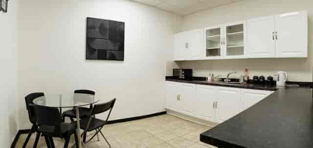 Modern kitchenette in 0161 Studios for networking events, featuring a sleek glass table.